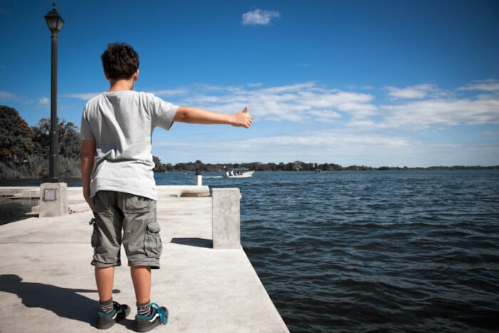 Little boy trying to hitchhike at an empty boat dock.