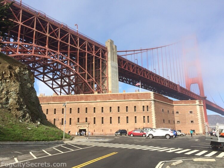 Fort Point under the Golden Gate Bridge, towers behind wisps of fog.