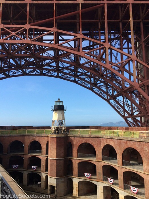 Courtyard and roof of Fort Point, with the steel arch of the Golden Gate Bridge above.