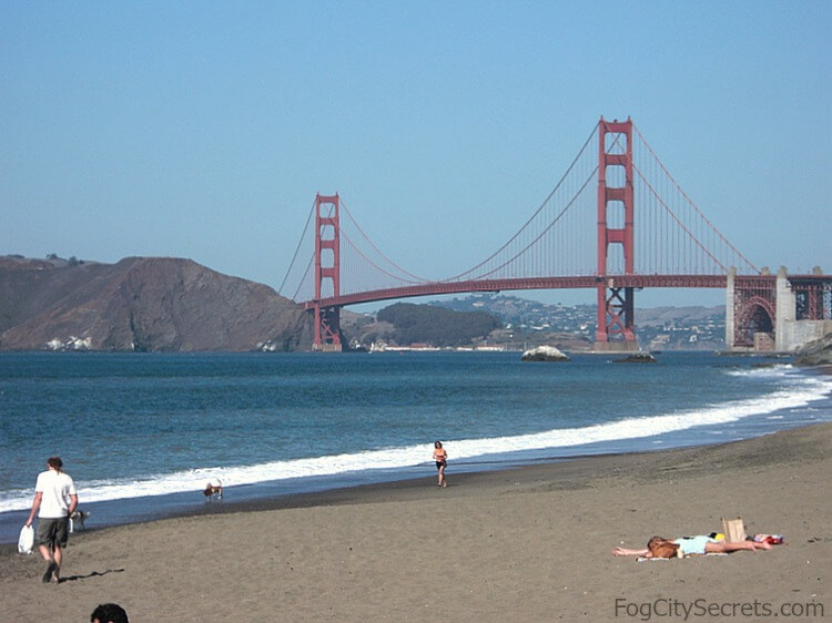 View of Golden Gate Bridge and sunbathers at western end of Baker Beach.